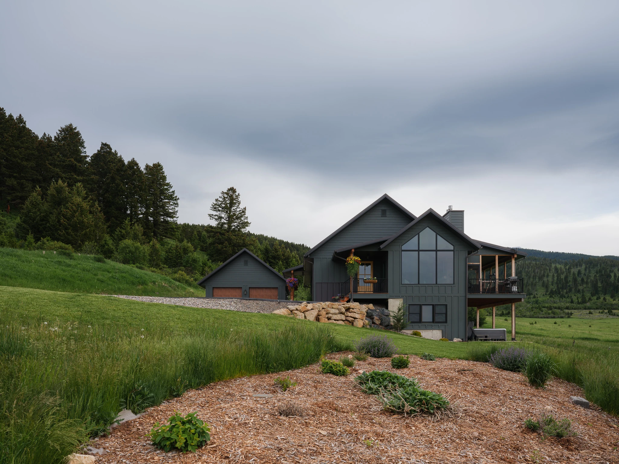 Exterior of the modern farmhouse-style home with gray siding and mountain backdrop — architectural photography Livingston Montana, Sam Schlauch Designs